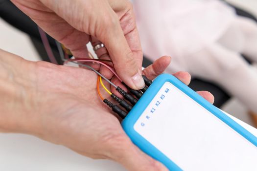 Doctor inserting the wires into a device to control a patient's responses during biofeedback therapy