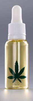 Closeup of bottle of marijuana oil on gray background. Hemp cosmetics concept