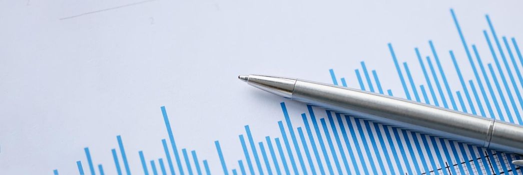 Metal ballpoint pen lying on documents with graph closeup. Management concept