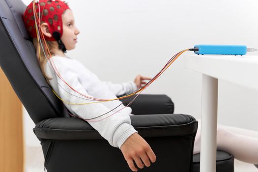 Profile of a girl sitting on a chair during a biofeedback session therapy in a clinic