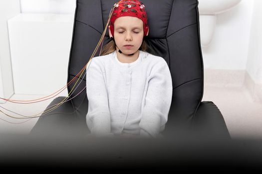Young girl sitting on a chair with eyes closed during a biofeedback session