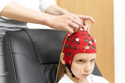 Cropped photo of a doctor attaching electrodes to a patient's headgear for biofeedback therapy.