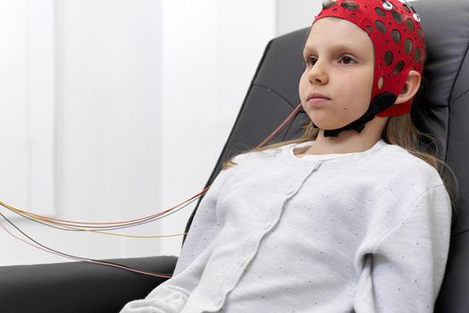 Caucasian girl sitting on a chair with serious expression during a biofeedback session in a clinic