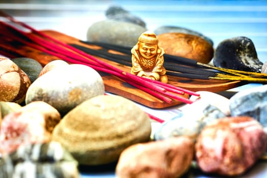 Think deeply or focus ones mind for a period of time, in silence, for religious or spiritual purposes or as a method of relaxation.Statuette of a Buddhist monk among incense and various stones