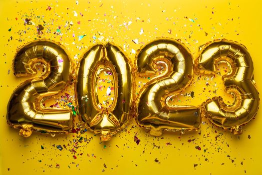 2023 concept Happy New Year from golden foil balloon on yellow background