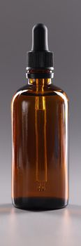 Closeup of glass bottle of cosmetic oil on gray background. Aromatherapy concept