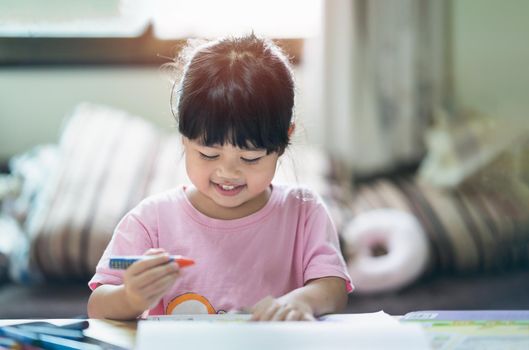 Cute little child painting with colorful paints. Asian girl using crayon drawing color.Baby artist activity lifestyle concept.