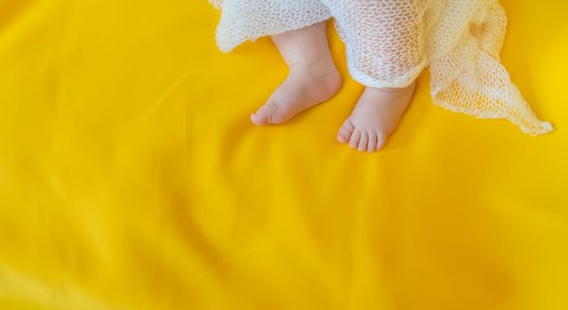 Baby feet on a yellow background. Selective focus. People. Merry Christmas and Happy New Year, Holidays greeting card background. Selective focus.