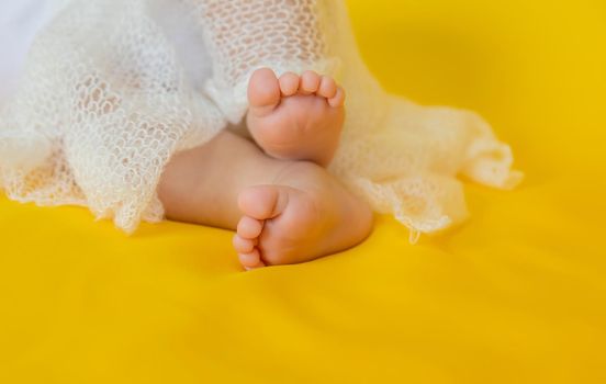 Baby feet on a yellow background. Selective focus. People. Merry Christmas and Happy New Year, Holidays greeting card background. Selective focus.