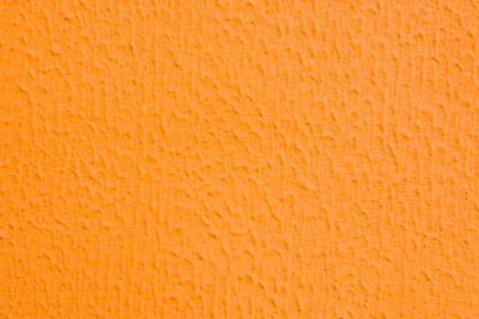 A wall with worn orange plaster.