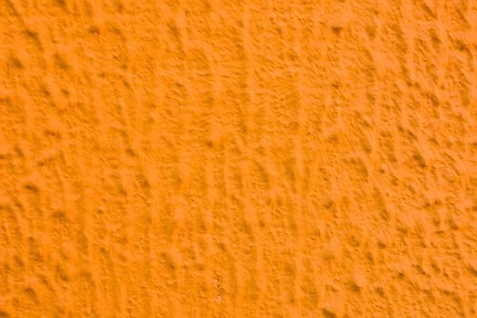 Relief texture of orange paint on the wall.