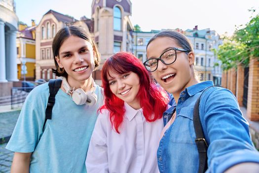 Having fun happy teenagers looking at camera, taking selfie. Three teenage friends together outdoor, on city street. Friendship, lifestyle, leisure, communication, youth concept