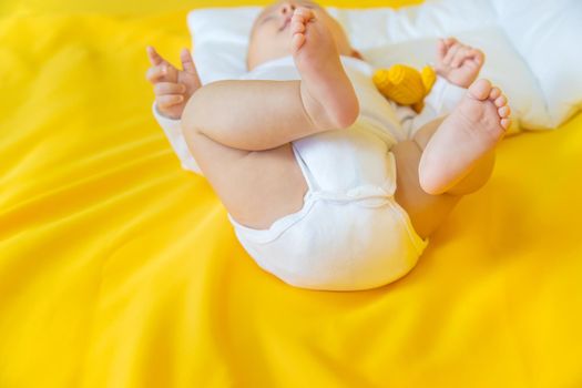 Baby feet on a yellow background. Selective focus. People. Merry Christmas and Happy New Year, Holidays greeting card background. Selective focus.