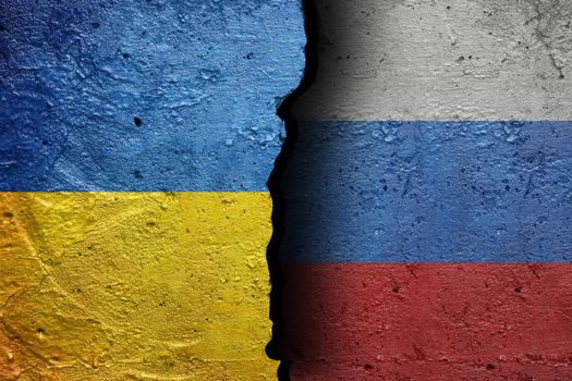 Ukraine and Russia - Cracked concrete wall painted with a Ukrainian flag on the left and a Russian flag on the right side