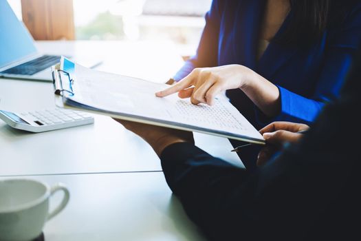 negotiation, analysis, discussion,asian female economist pointing out a document explaining the investment finance program to the company owner to plan marketing and hedging business risks