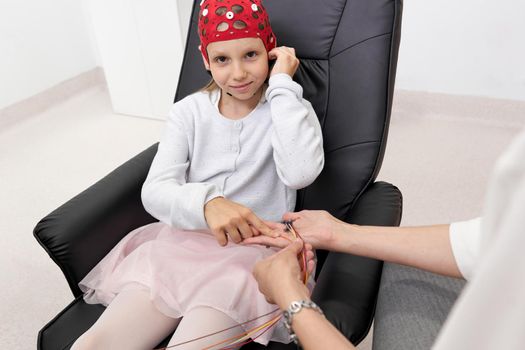 Kid sitting on a chair next to a doctor ready to start a biofeedback treatment