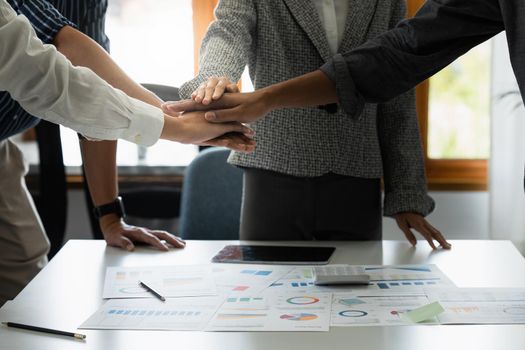 Group of business people putting their hands working together on wooden background in office. group support teamwork agreement concept