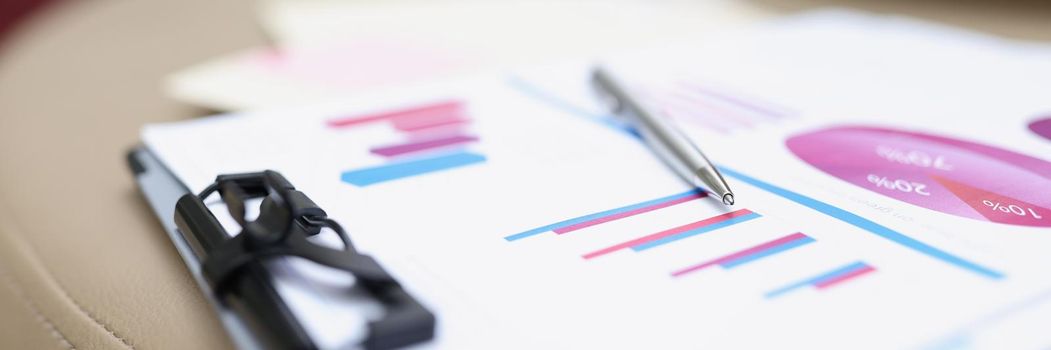 A folder with documents lies on a leather surface, close-up, blurry. Audit preparation, color chart and graph on paper