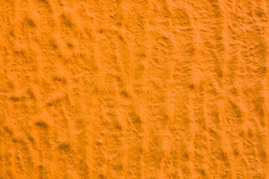 Uneven abstract texture of yellow paint. Abstract background of orange plaster.