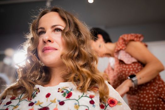 A female customer slightly smiles with confidence during a hairdressing session at the hair salon