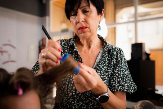 A female hairdresser curling a lock of her client's hair during a hairdressing session at the hair salon