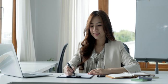 Portrait of an Asian young business Female working on a laptop computer in her workstation.Business people employee freelance online report marketing e-commerce telemarketing concept..