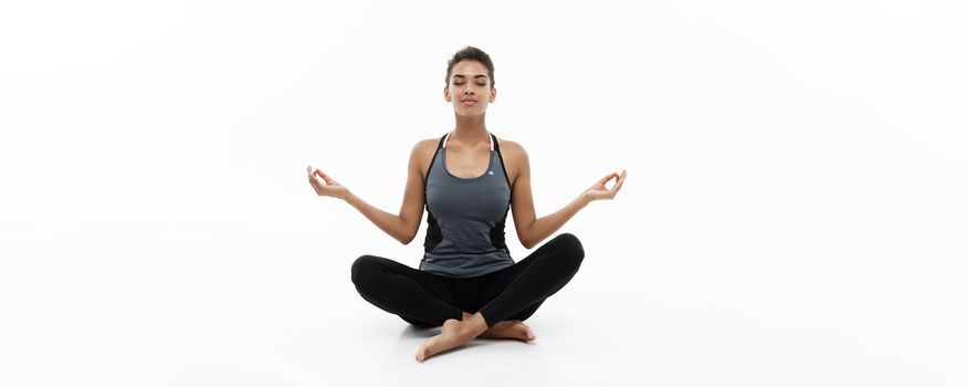 Healthy and Fitness concept - Beautiful American African lady in fitness clothing doing yoga and meditation. Isolated on white background