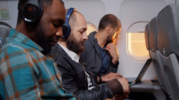 Entrepreneur browsing internet on smartphone during flight, travelling by airplane transportation on work trip. Flying with international airline using mobile phone during sunset.