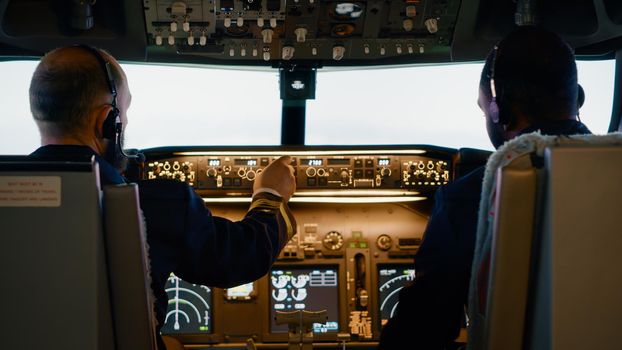 Diverse team of aviators preparing to takeoff with airplane, fixing altitude and longitude levels to fly aircraft. Getting ready for aerial flight using control panel command and dashboard.