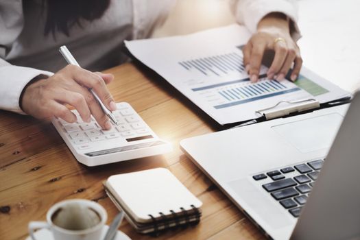 Business woman using calculator to review balance sheet annual using document and laptop computer to calculating budget. audit and Check integrity before investment concept