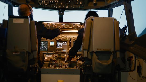 Captain and copilot inserting destination coordinates and fixing altitude and longitude level on dashboard command in cockpit. Using control panel to fly airplane and takeoff.