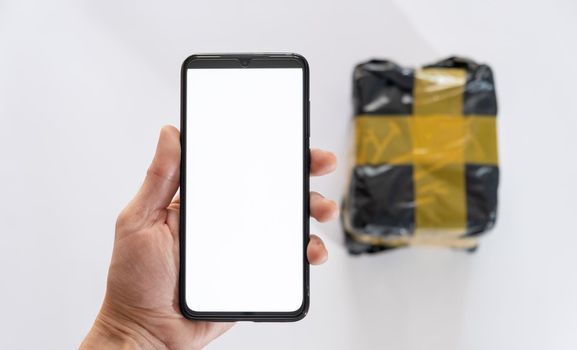 hand holding mobile phone with parcel package on white background. delivery tracking concept