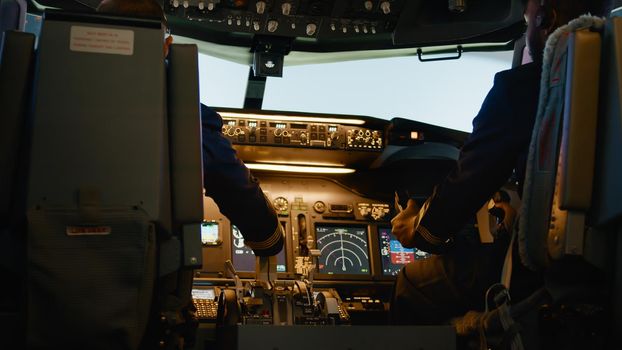 Diverse team of aviators throttling engine lever to takeoff, using handle and dashboard command to fly airplane. Control panel navigation with power switch in cockpit.