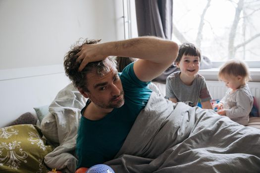 Mature man waking up surrounded with children. morning in the bed