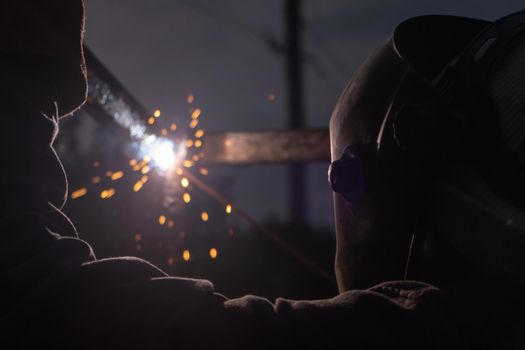 Worker with protective mask welding metal and producing smoke and sparks. arc welding. welder working welding steel