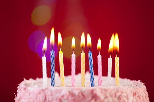 happy birthday cake shot on a red background with candles