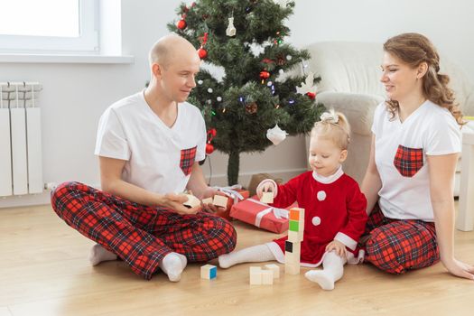 Baby child with hearing aid and cochlear implant having fun with parents in christmas room. Deaf and health