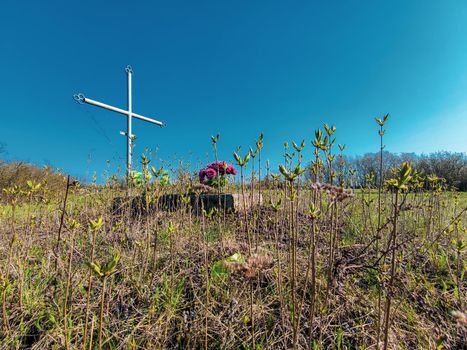 Aged cross tomb with flowers and overgrown grass. wake old christian traditional. old grave