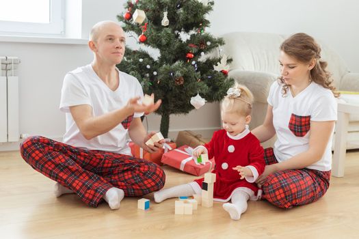 Baby child with hearing aid and cochlear implant having fun with parents in christmas room. Deaf and health