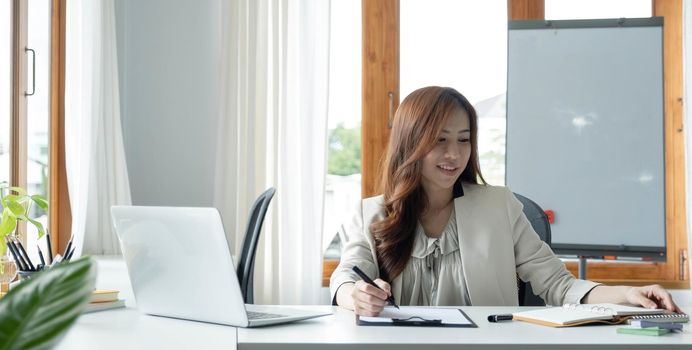 Portrait of an Asian young business Female working on a laptop computer in her workstation.Business people employee freelance online report marketing e-commerce telemarketing concept..