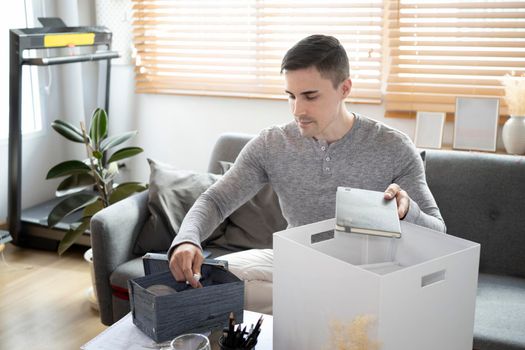 Man sitting on sofa preparing personal stuff for moving into new house.