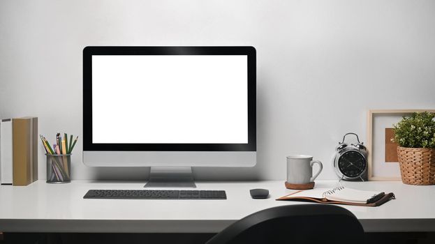 Contemporary workplace with computer pd, coffee cup, houseplant and stationery on white table.