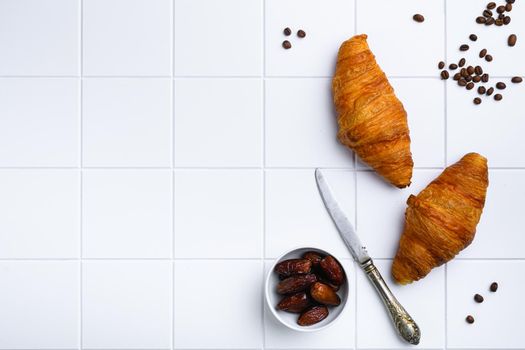 Fresh baked croissant, on white ceramic squared tile table background, top view flat lay, with copy space for text