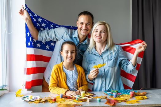 family holding american flag around autumn leaves