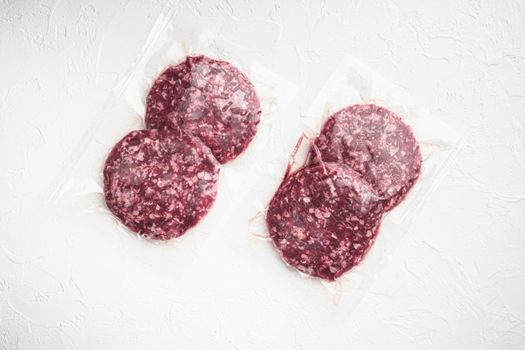 Beef patties in a vacuum packing set, on white stone background, top view flat lay