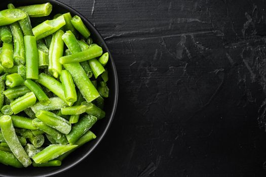 Frozen green beans set, in bowl, on black stone background, top view flat lay, with copy space for text