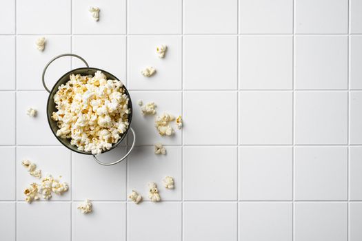 Heap of delicious popcorn, on white ceramic squared tile table background, top view flat lay, with copy space for text