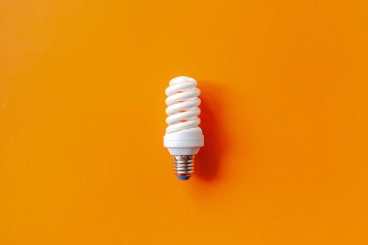 Energy saving light bulb on a orange background. Economical consumption of electricity. The concept of nature conservation