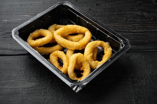 Heap of deep fried squid or onion rings package set, on black wooden table background, with copy space for text