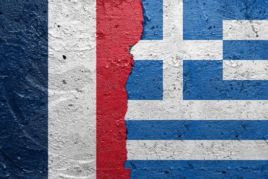 France and Greece - Cracked concrete wall painted with a French flag on the left and a Greek flag on the right